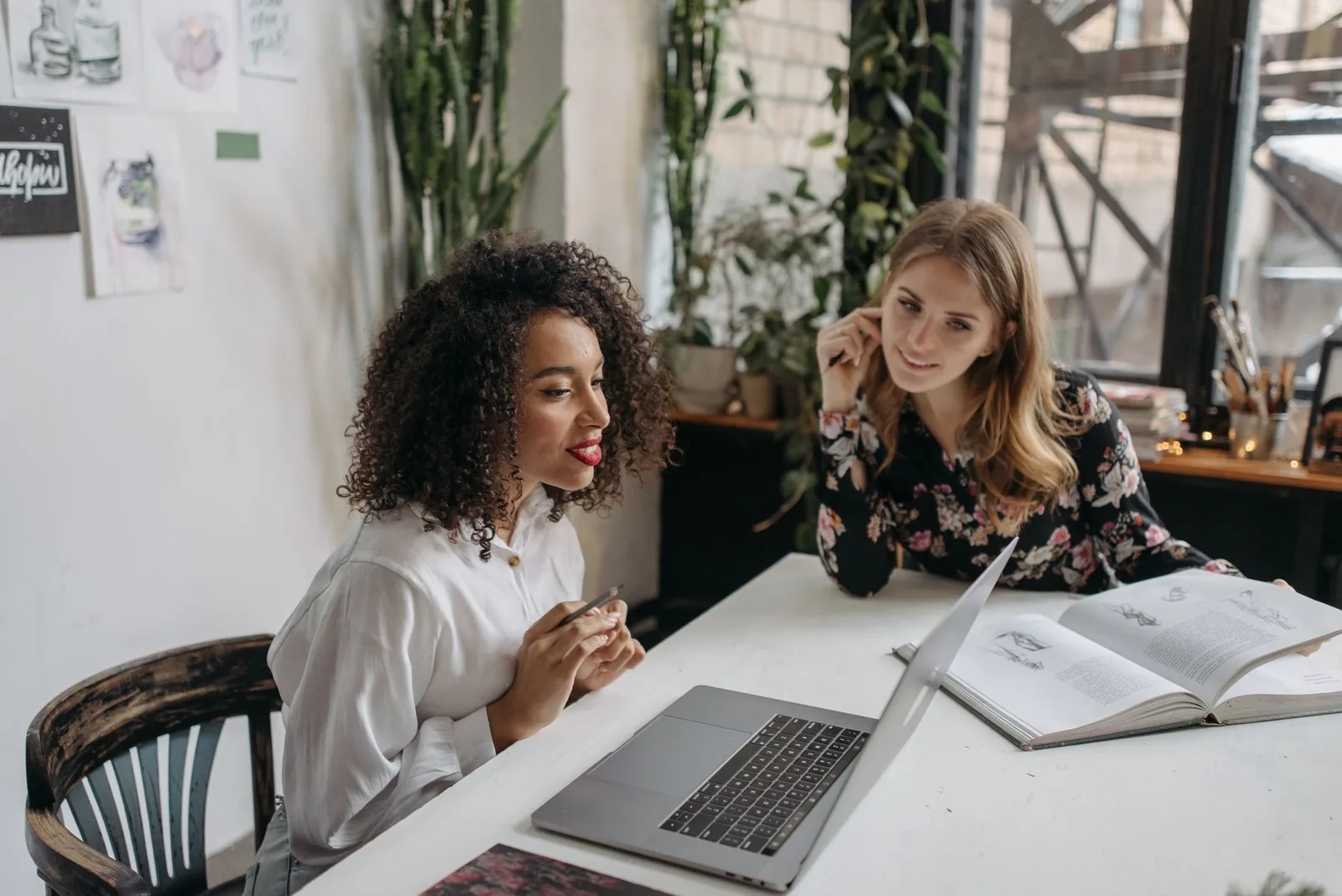 Twee vrouwen werken samen aan een laptop in een lichte studio