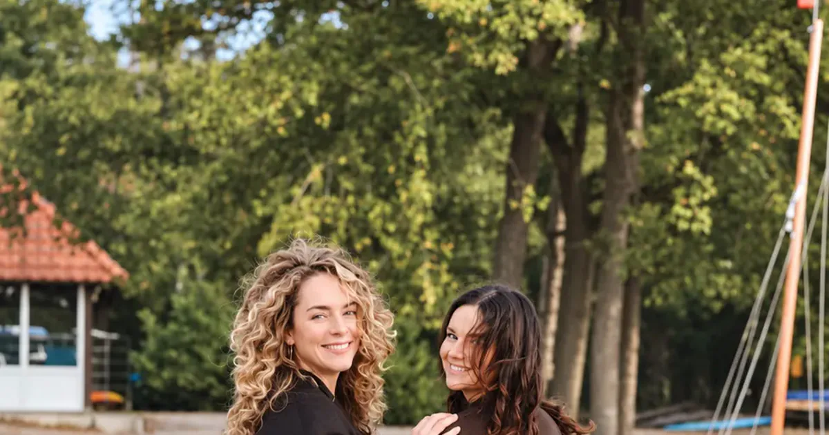 Twee ondernemende vrouwen in zwarte outfits kijken lachend om op een steiger