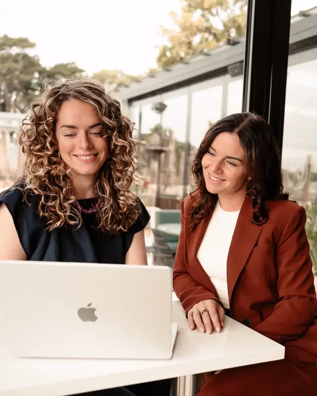 Heleen en Cristel werken samen achter een laptop