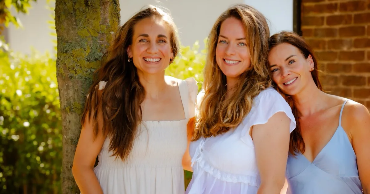 Drie vrouwen van Healthy Business Women staan lachend samen in de zon