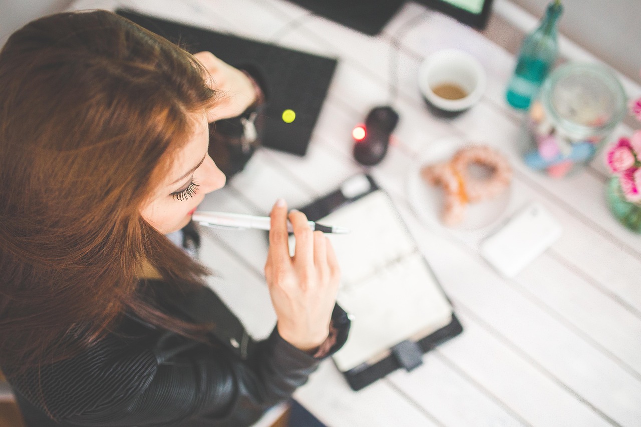 Vrouw leest aandachtig informatie aan haar bureau met agenda en telefoon binnen handbereik