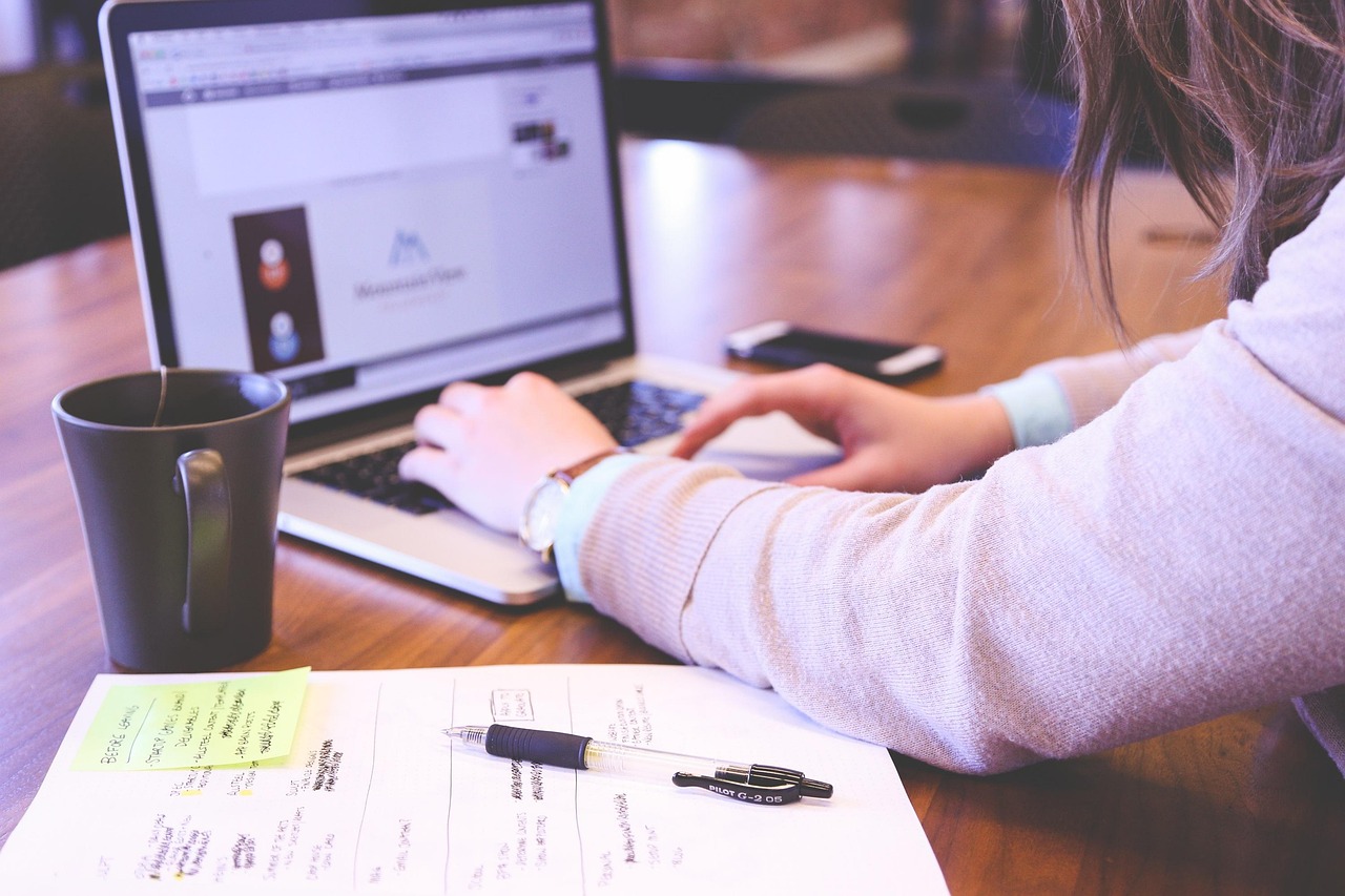 Vrouw zoekt achter haar laptop reviews en ervaringen op, met aantekeningen naast zich